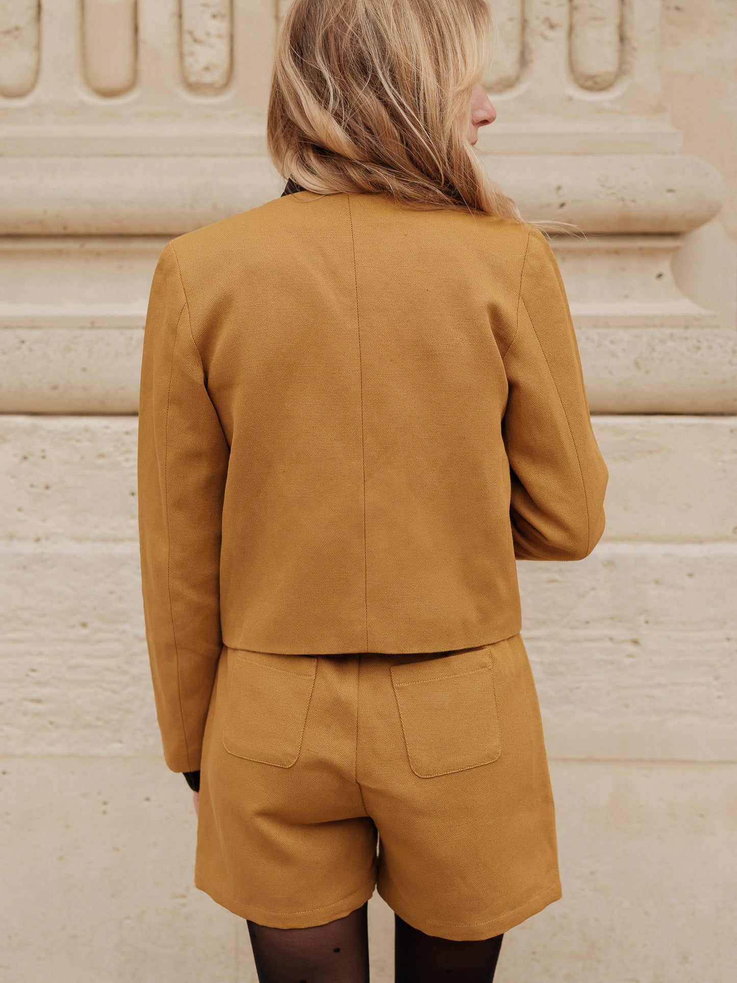 short structuré revisité, allure féminine audacieuse, coupe moderne droite courte, minimalisme graphique, style urbain assumé, pièce forte automne hiver, coton laine, short court, bouton bijoux ANTIGONE, ANTIGONE Paris, marque de prêt-à-porter premium femme, tailleur femme élégant, ensemble coordonné chic, power suit féminin, ANTIGONE Paris, ANTIGONE, matching set