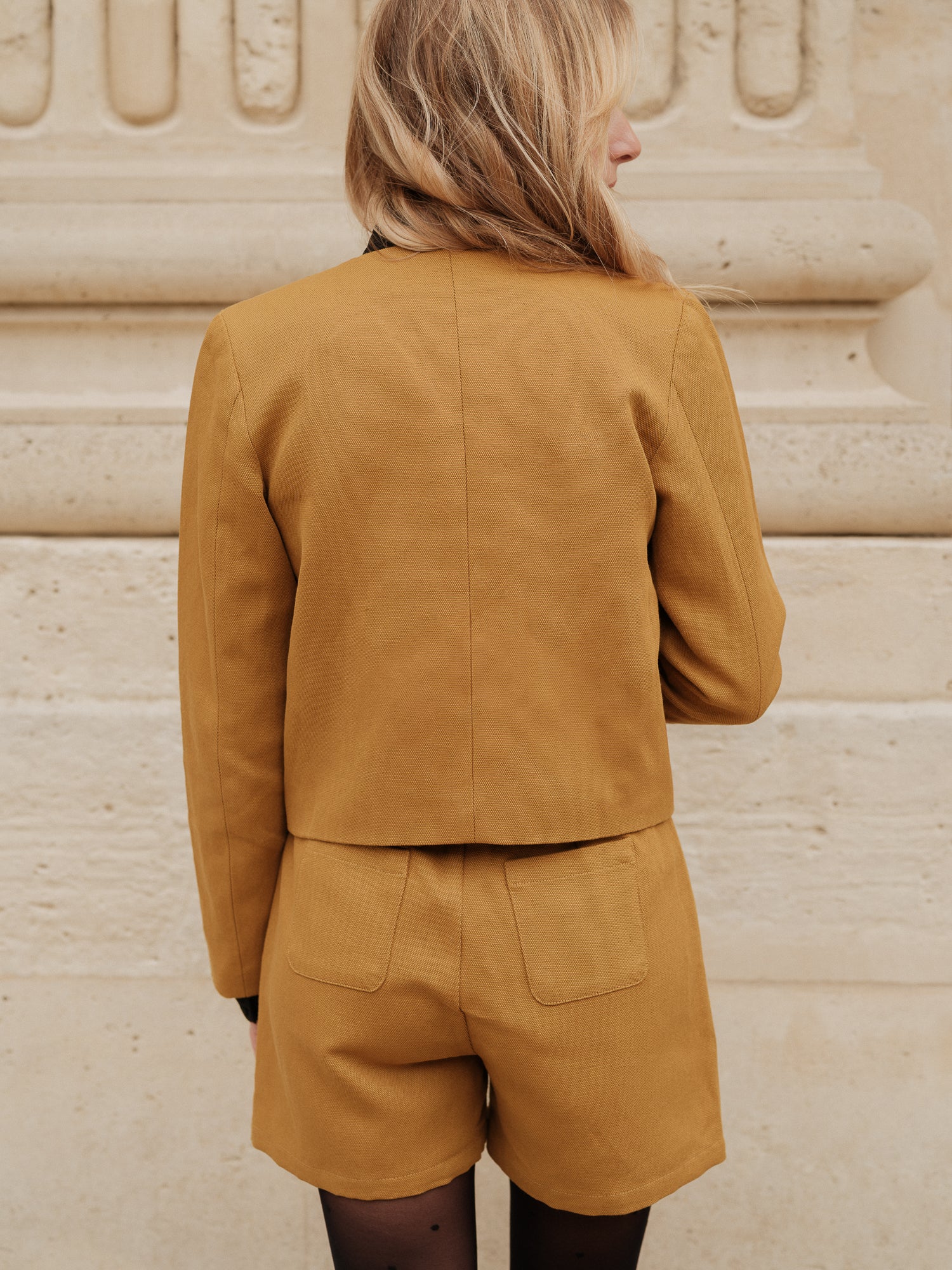 short structuré revisité, allure féminine audacieuse, coupe moderne droite courte, minimalisme graphique, style urbain assumé, pièce forte automne hiver, coton laine, short court, bouton bijoux ANTIGONE, ANTIGONE Paris, marque de prêt-à-porter premium femme, tailleur femme élégant, ensemble coordonné chic, power suit féminin, ANTIGONE Paris, ANTIGONE, matching set
